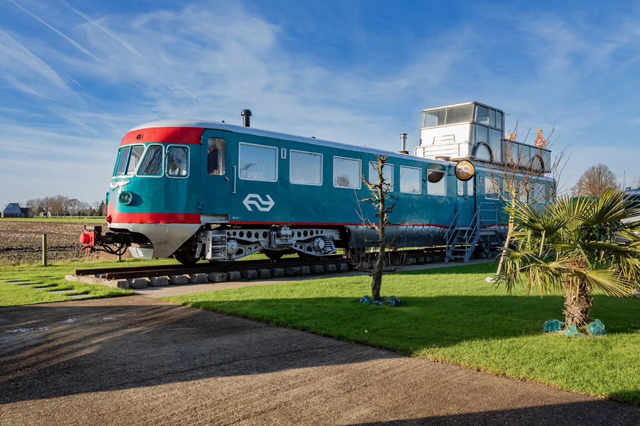 Een gerenoveerde, oude Blauwe Engel (trein) staat op het erf van de woonboerderij en dient nu als B&B.