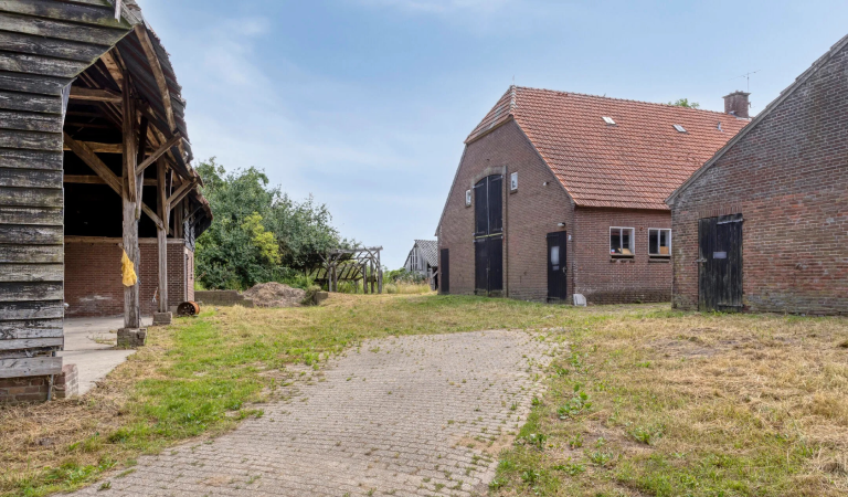 Buitenaanzicht van het woonverblijf van wederopbouwboerderij 't Heyendaal, met op de voorgrond de oude schuur.