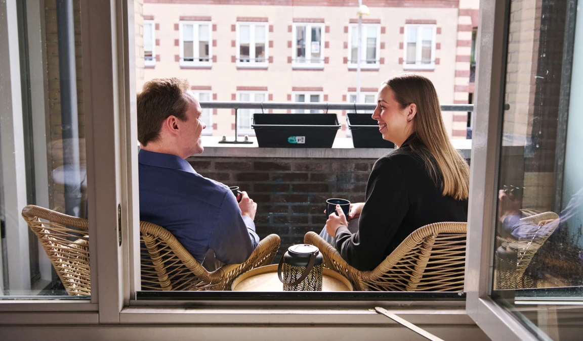 Juliet en Robbert zitten op het balkon van hun huurappartement.