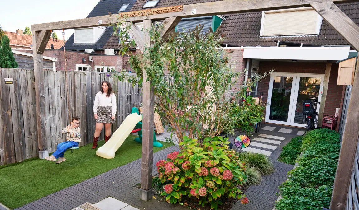 Lieke met haar zoontje Daan in de achtertuin, met op de achtergrond de uitbouw.