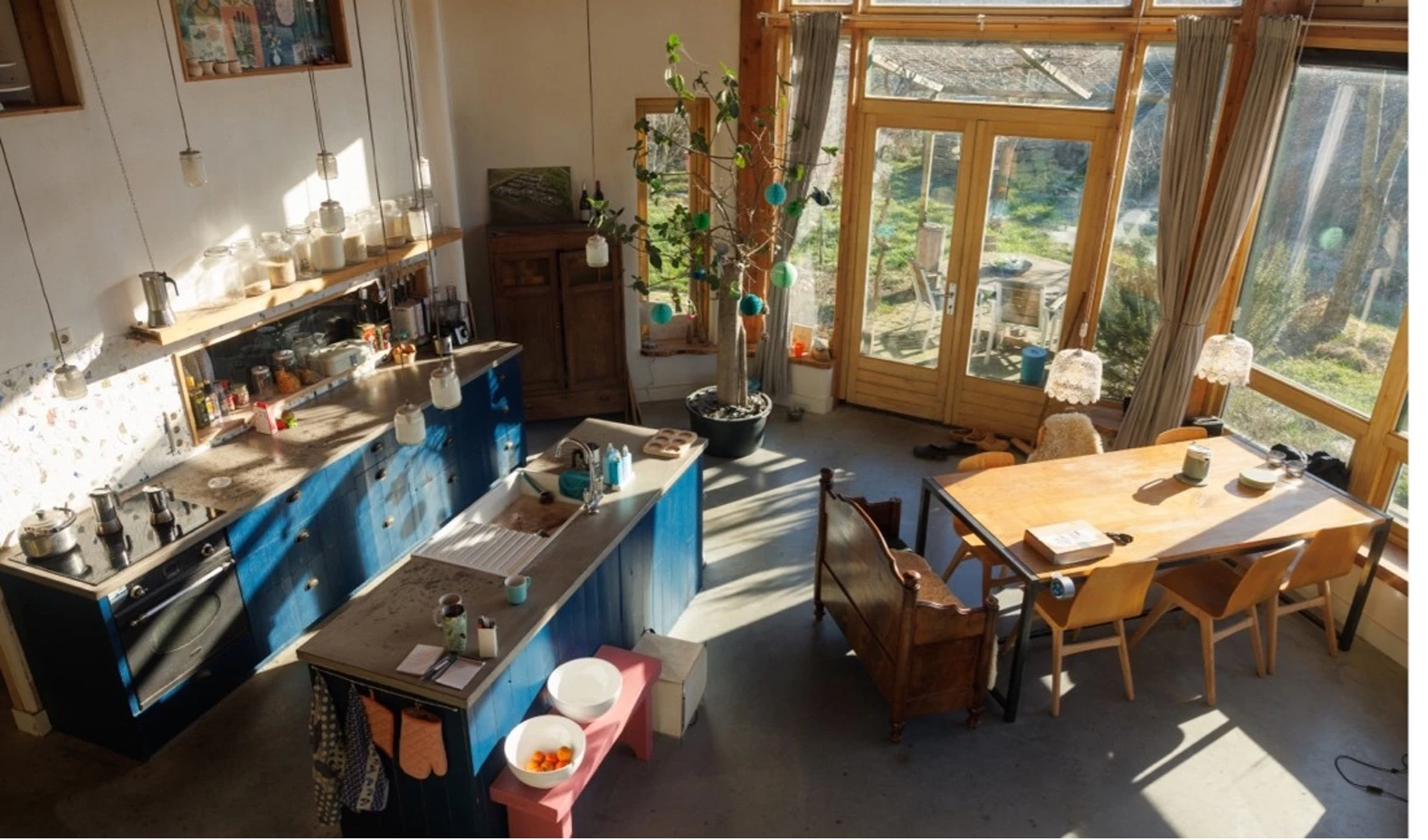 Bovenaanzicht van het interieur van het aardehuis, met links de keuken en rechts de eettafel.