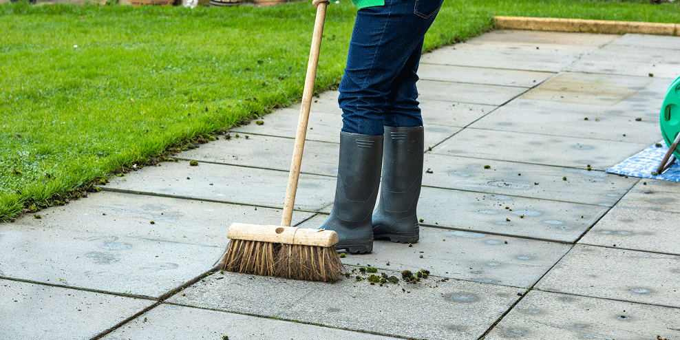 Iemand is het buitenterras met een bezem aan het schoonmaken.
