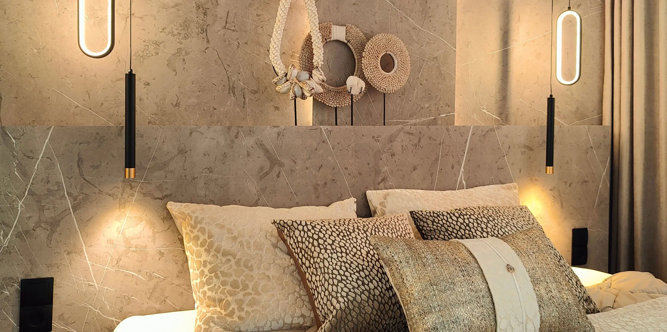 Bed met een hotel-chique wandpanel in aardtinten als achterbord.