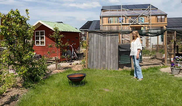 Marjolein Jonker staat in de tuin van haar tiny house op het gras.
