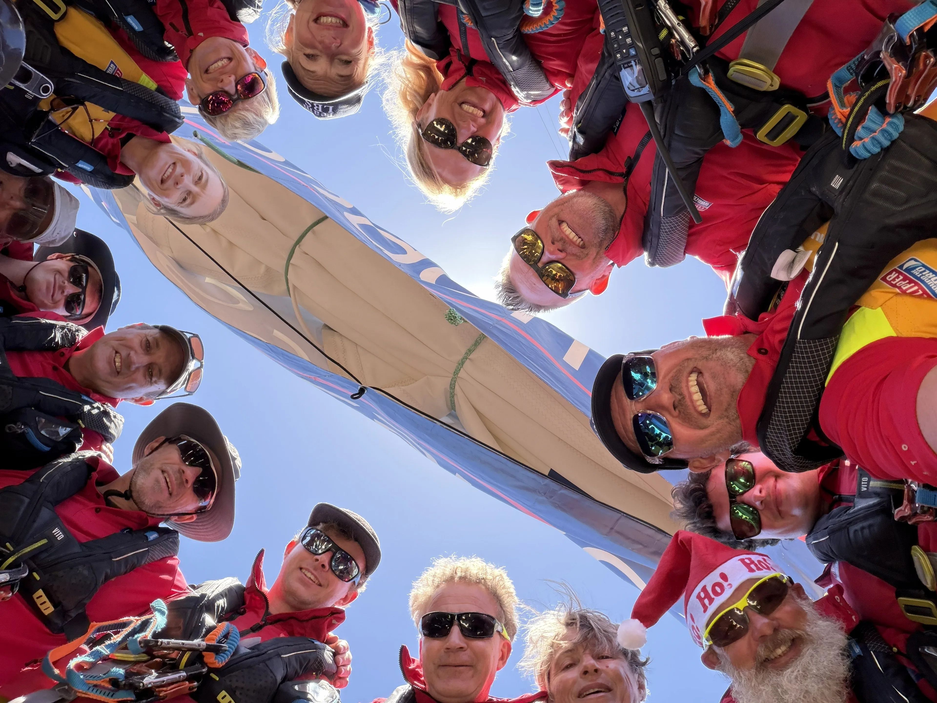 Team London Business School crew members gathered in a circle on deck, smiling for a group selfie aboard their Clipper Race yacht during an offshore sailing challenge.