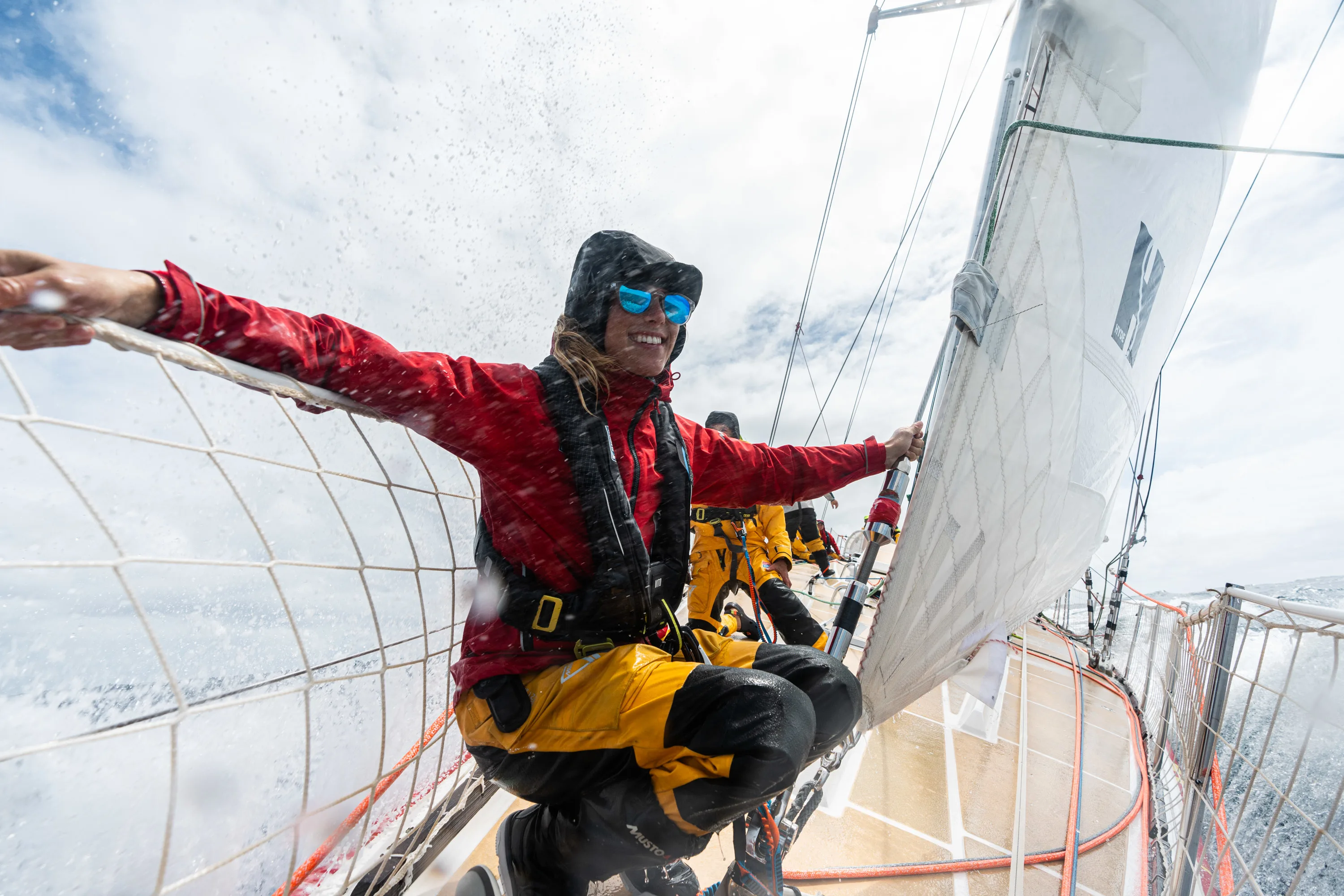 Woman at the foredeck, smiling holding onto shroud