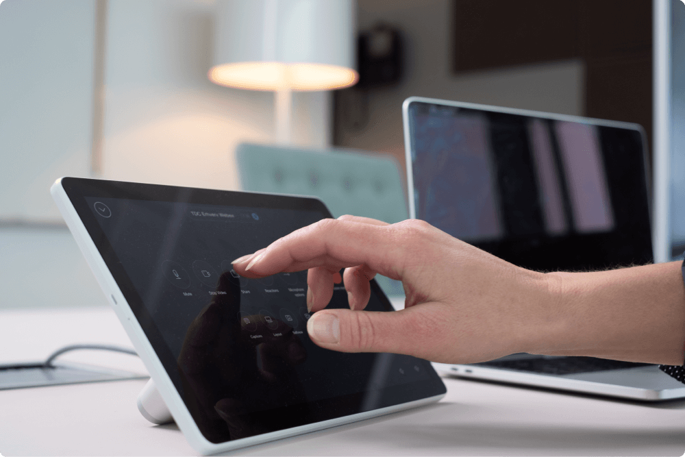 Billedet viser en touch pad med en hånd der trykker på skærmen til Cisco Webex.
