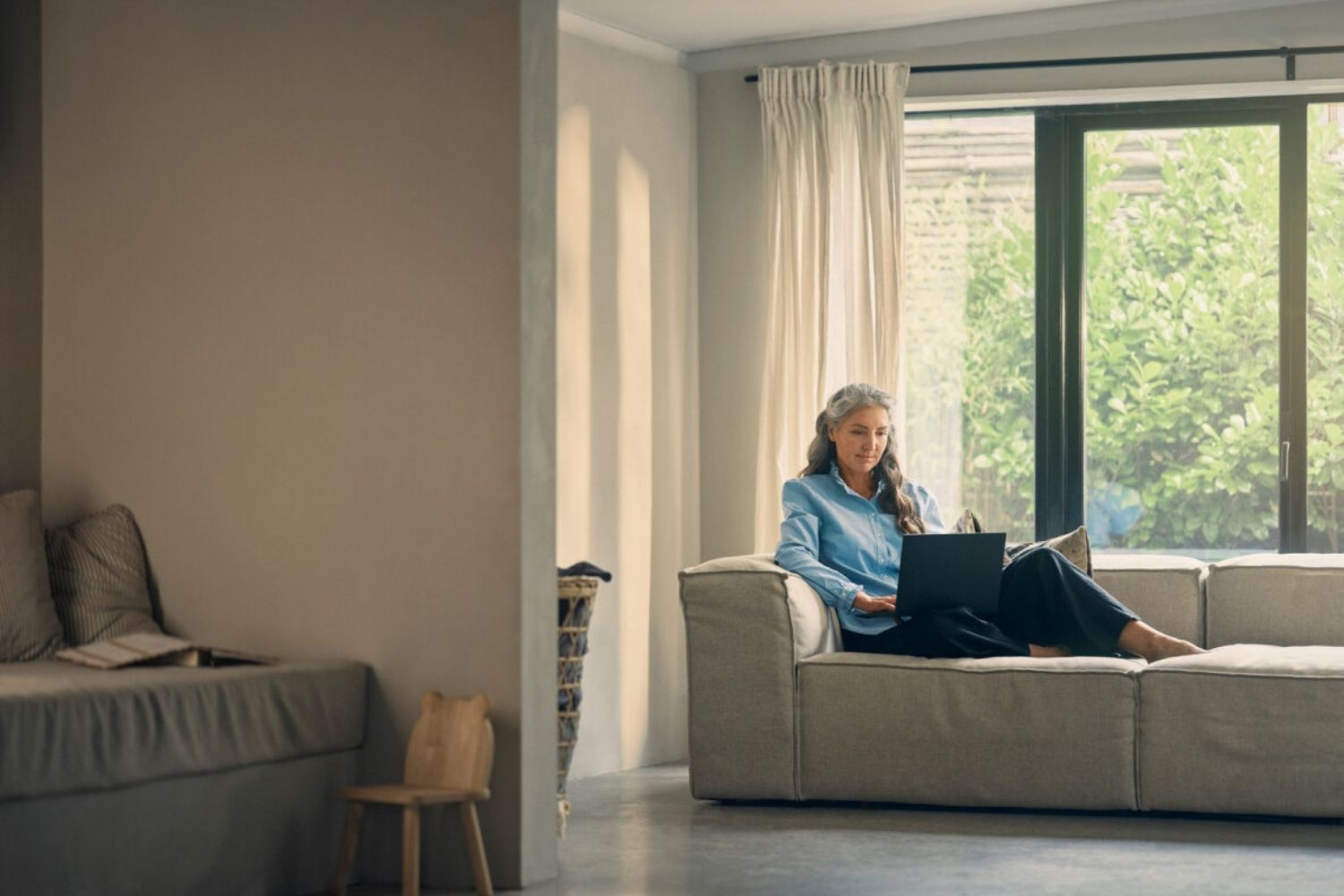 En kvinde sidder på sofaen og arbejder hjemmefra