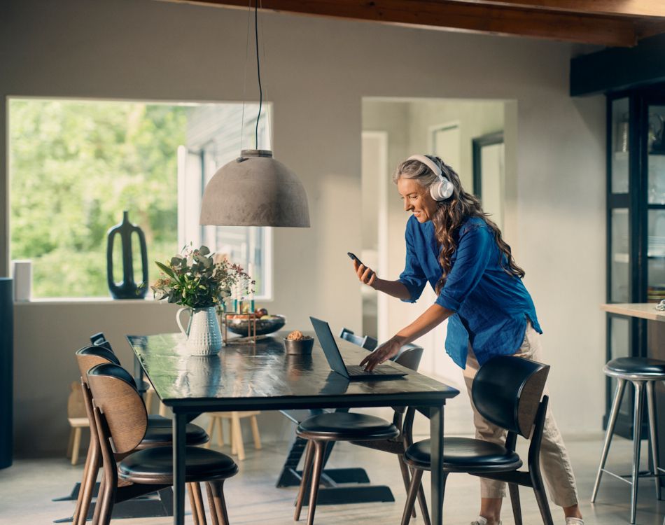 Kvinde med hovedtelefoner på står og ved et spisebord