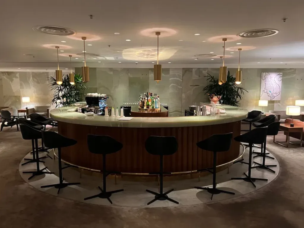 The circular bar at the Cathay Pacific First Class Lounge, The Pier, in Hong Kong, lit by hanging brass pendant lights