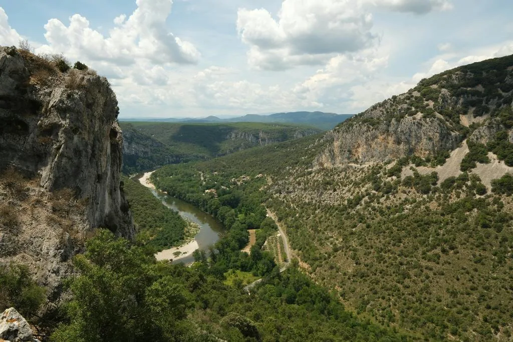 Aerial view of the Ardèche Gorge in France, with a winding river cutting through steep limestone cliffs and forested hillsides
