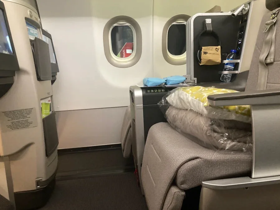 TAP Air Portugal A321LR business class cabin showing window seats with a blanket and amenity kit on the seat.