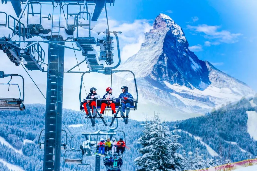 Skiers riding a chairlift with the snow-capped Matterhorn peak rising in the background in Switzerland