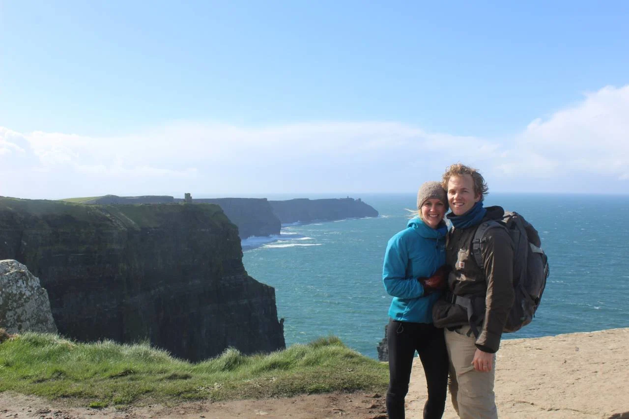 A couple traveling abroad with duffel bags, illustrating a 17-month honeymoon funded by points.