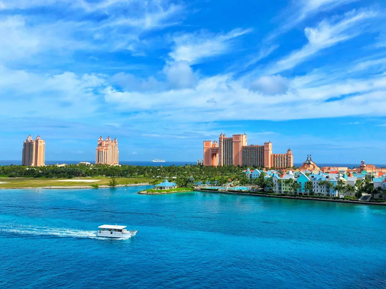 The pink towers of the Atlantis resort in Nassau, Bahamas, viewed across turquoise water with a boat passing by