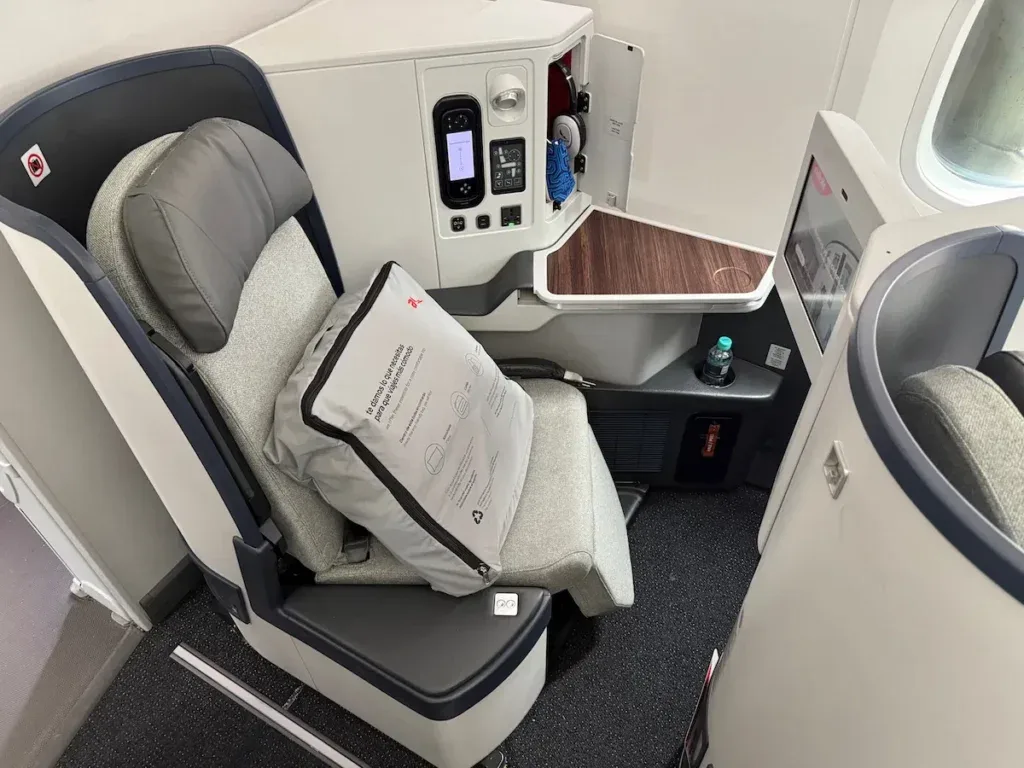 An Avianca business class seat on a Boeing 787-9 with an amenity kit bag on the cushion and a fold-out tray table