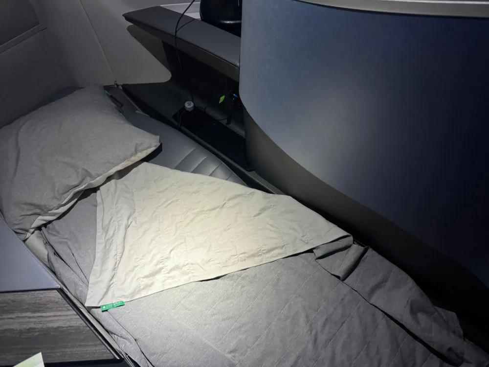 A JetBlue Mint seat converted into a lie-flat bed with a pillow and blanket on an A321XLR