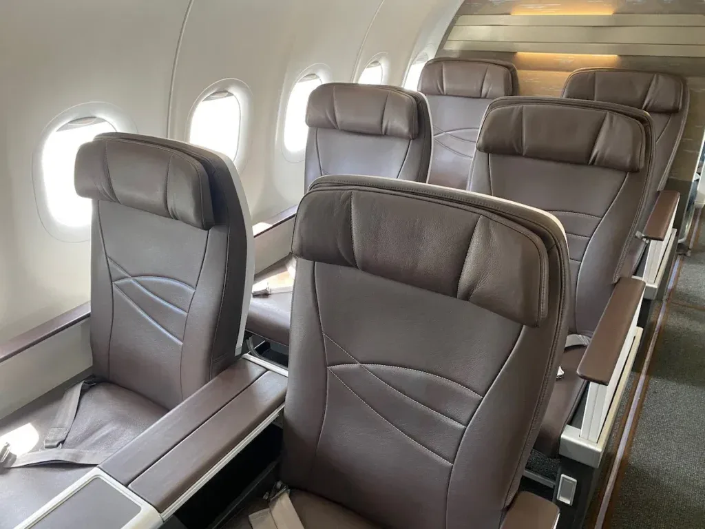 Rows of brown leather recliner seats in Hawaiian Airlines first class aboard an Airbus A321neo