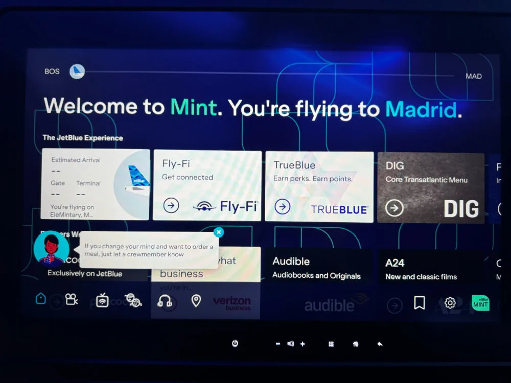 JetBlue Mint seatback entertainment screen welcoming a passenger on a flight from Boston to Madrid, with menu tiles for Fly-Fi, TrueBlue, and in-flight entertainment