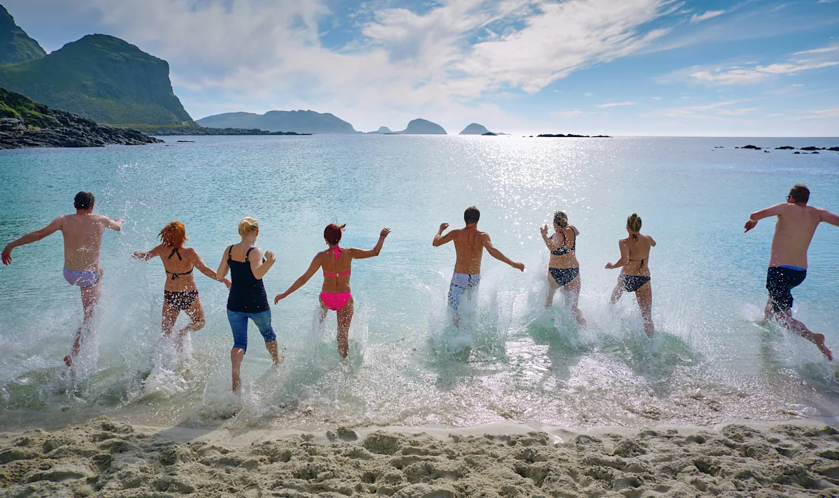 people running into water on beach 