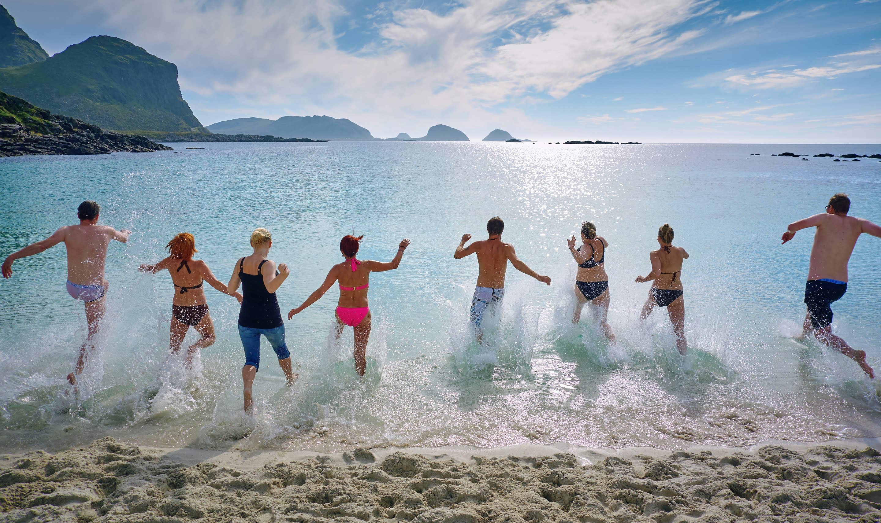 people running into water on beach 