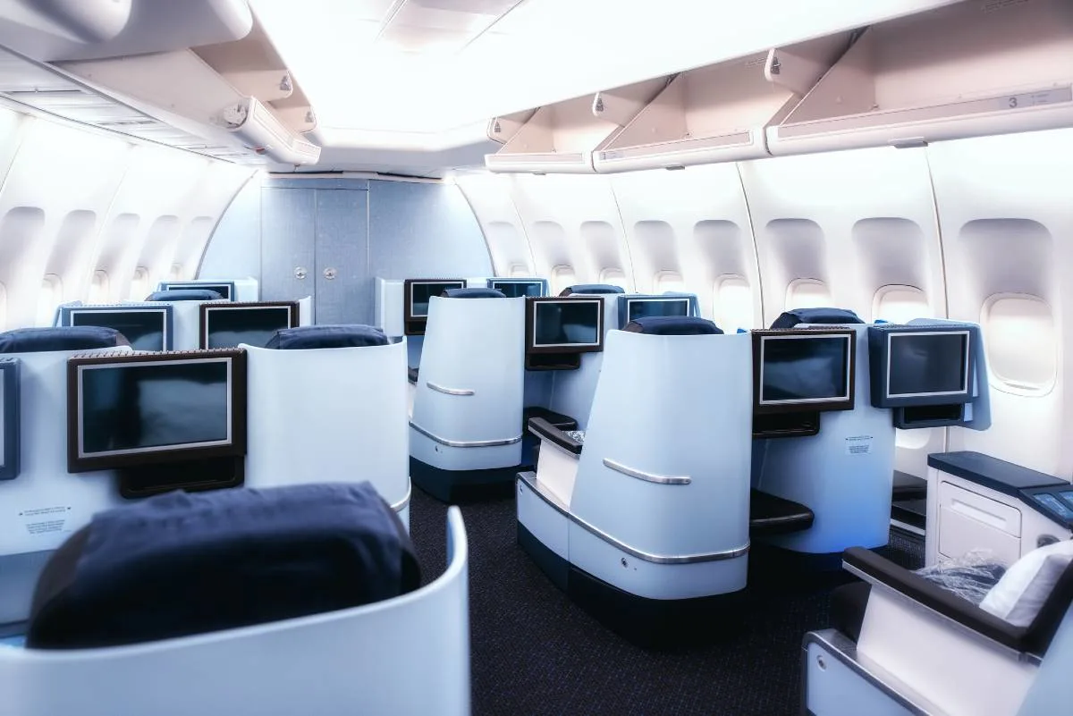 A business class seat beside a first class suite, illustrating the difference between the two cabins.