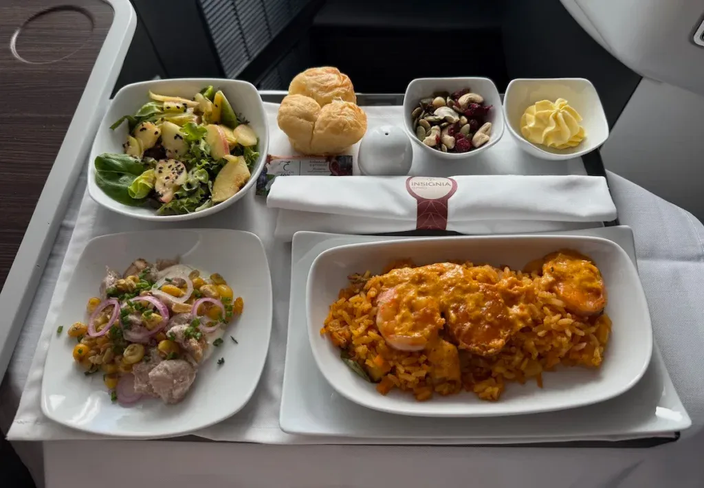 An Avianca business class meal tray with salad, bread rolls, a ceviche-style dish, and shrimp over rice