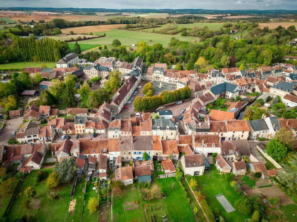 Aerial view of a Burgundy village with red-tiled roofs surrounded by green countryside