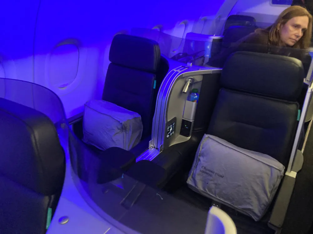 JetBlue Mint business class suite aboard an A321 with a lie-flat seat illuminated by blue cabin lighting