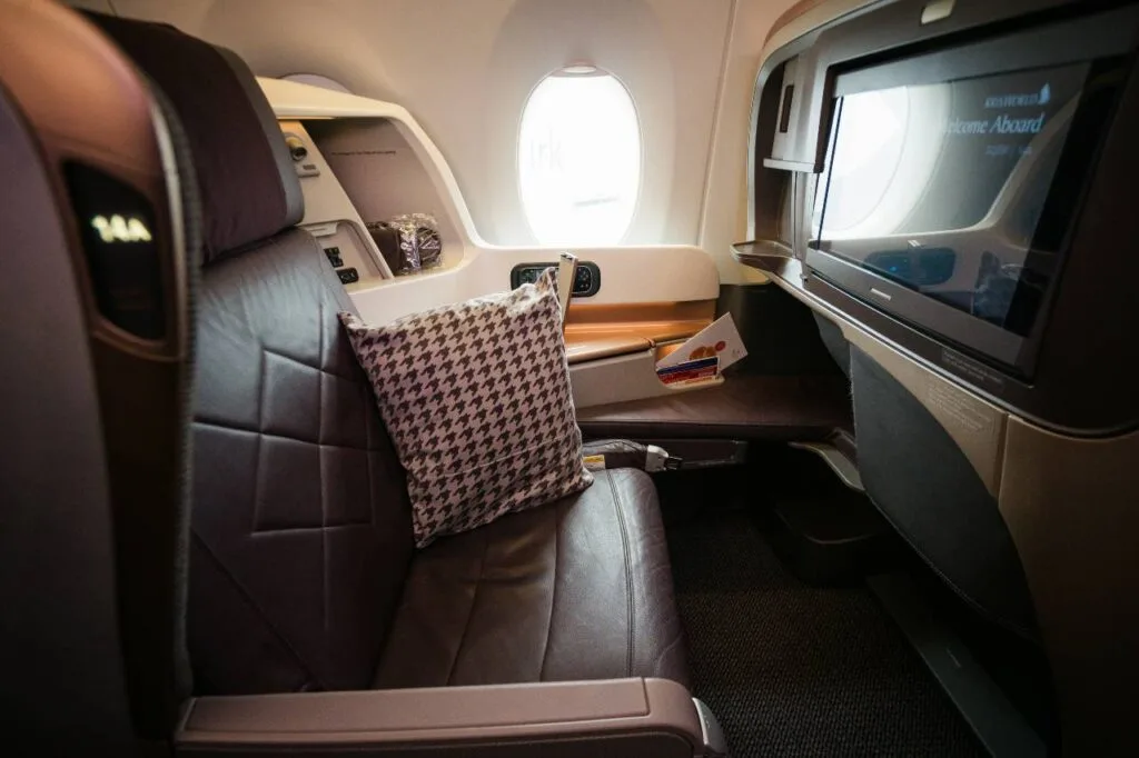 Singapore Airlines business class seat with a houndstooth pillow, seen next to the window and entertainment screen