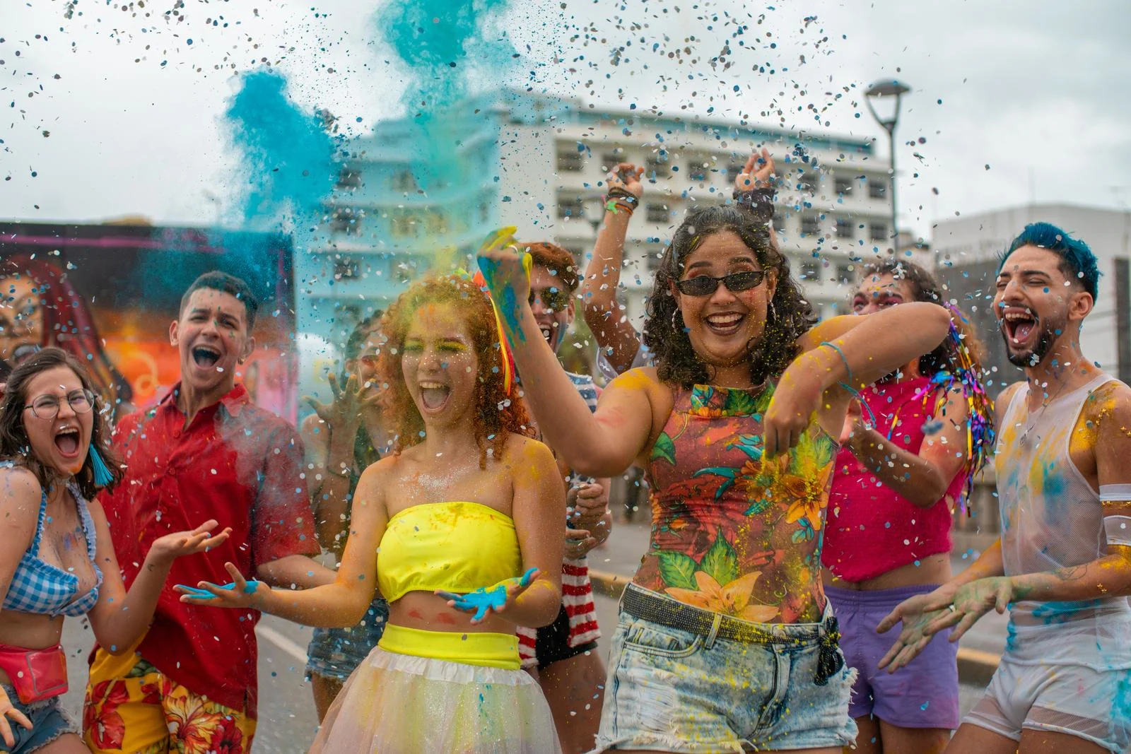 Joyful young people at São Paulo Pride covered in colored powder, with bright blue powder spraying through the air. Young marchers covered in colored powder celebrate at São Paulo Pride, one of the largest Pride parades in the world, drawing three to five million people each year.