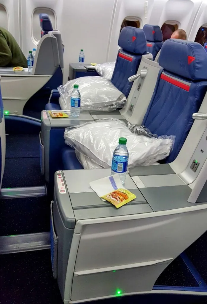 A Delta One business class meal service tray with a salad, a bread roll with butter, and a side of dressing