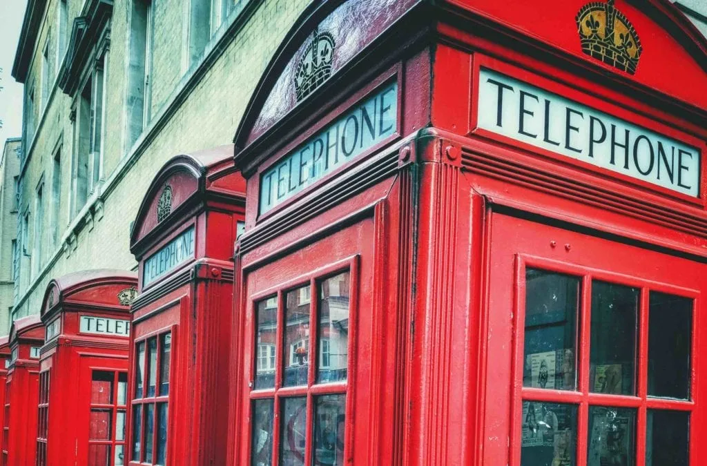 A row of classic red telephone boxes lining a street in London