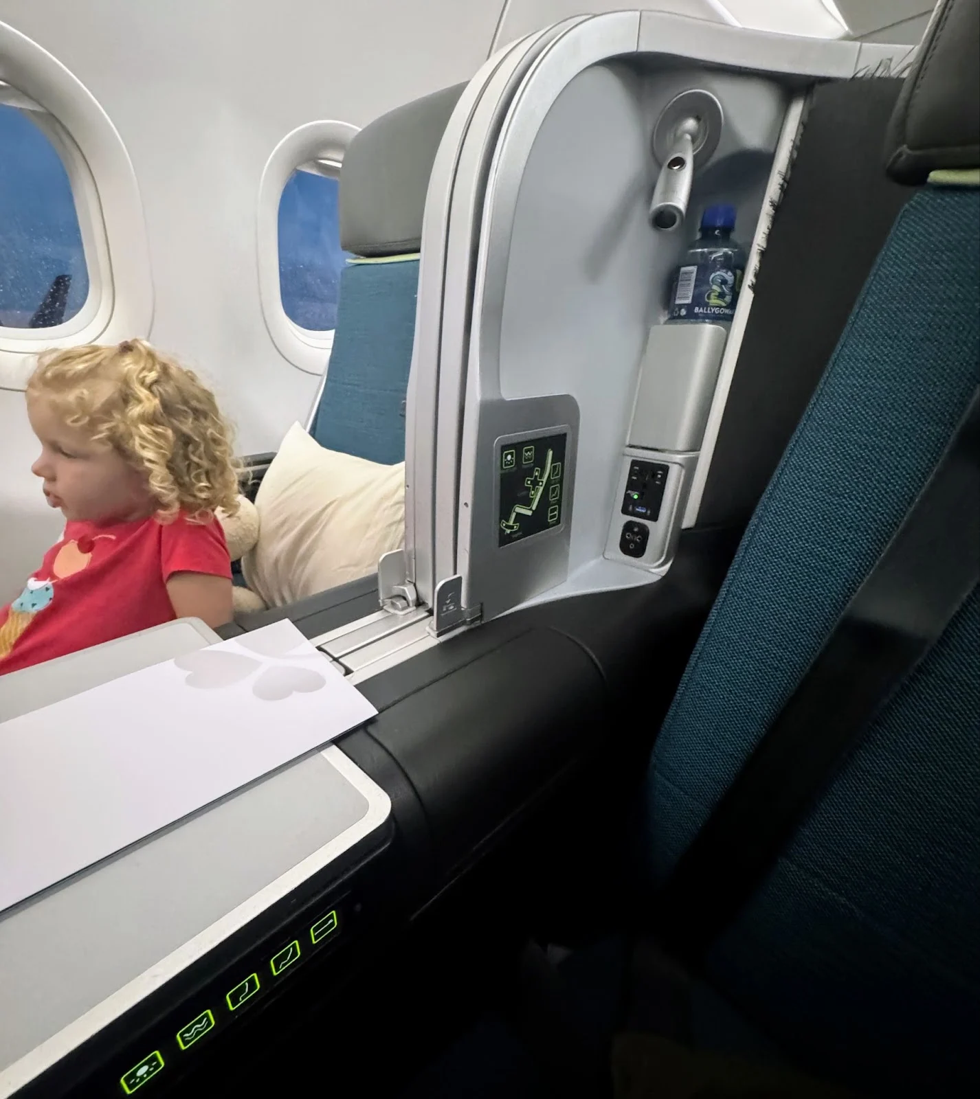 A toddler seated in an Aer Lingus business class seat looking out the window during a flight