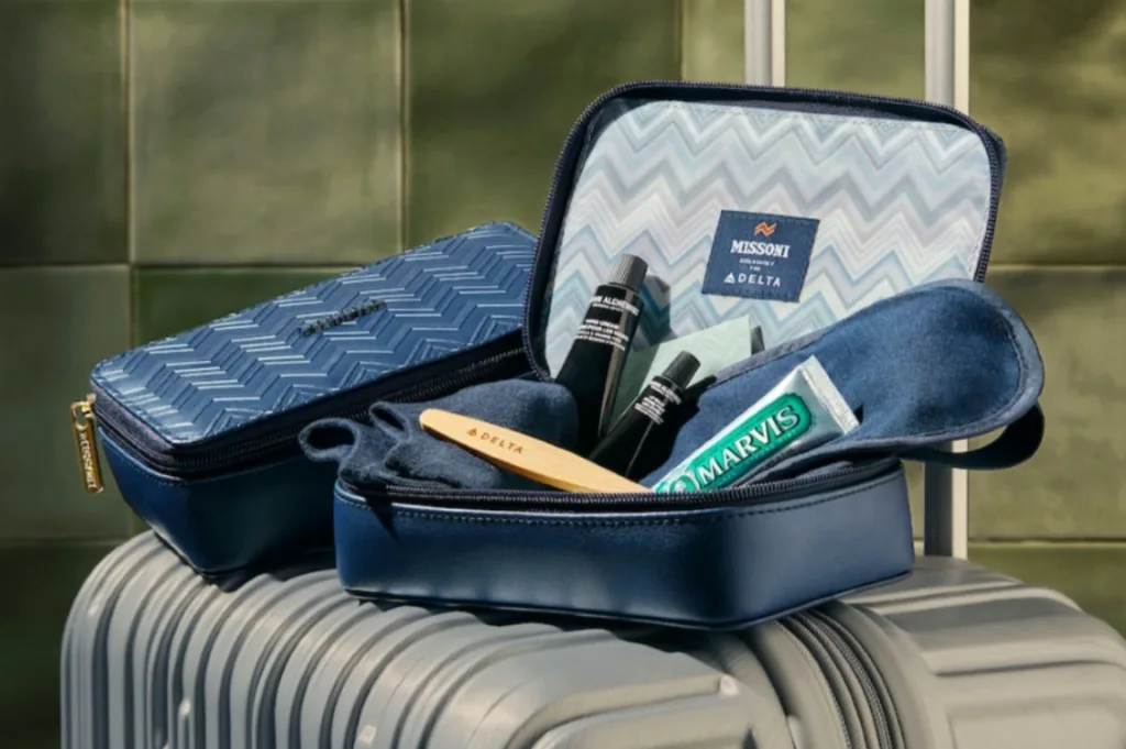 A Missoni for Delta One amenity kit opened to show toiletries, an eye mask, and a Marvis toothpaste tube atop a suitcase