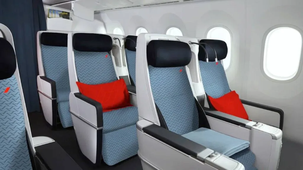 Rows of Air France premium economy seats with red headrest pillows and blue upholstery