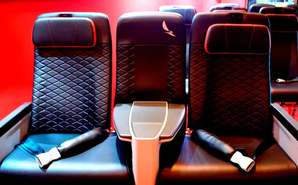 Close-up of Avianca premium economy seats with red headrest accents and a bird logo on the center seatback