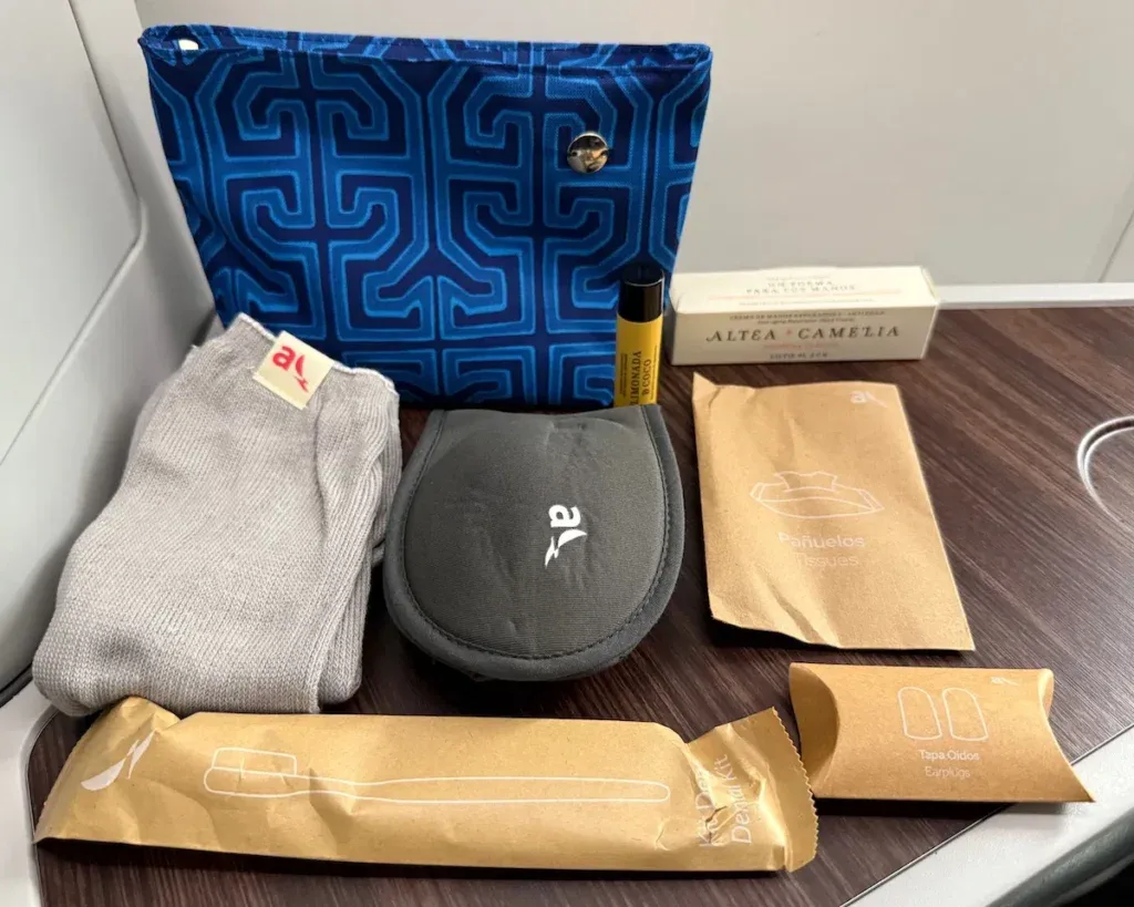 Avianca business class amenity kit displayed on a tray table, including socks, lip balm, tissues, and a dental kit