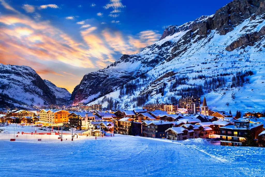 The illuminated alpine village of Val d'Isère, France, glows beneath snow-covered peaks at sunset