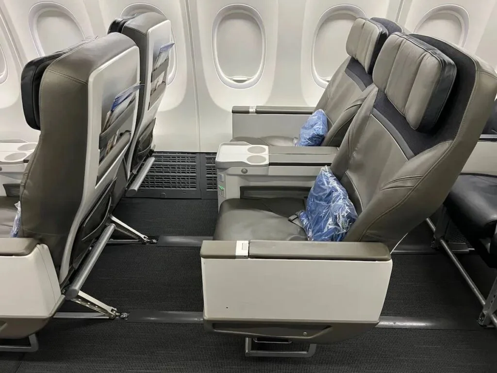 Alaska Airlines 737 MAX first class recliner seat with tray table extended, shown next to airplane windows.