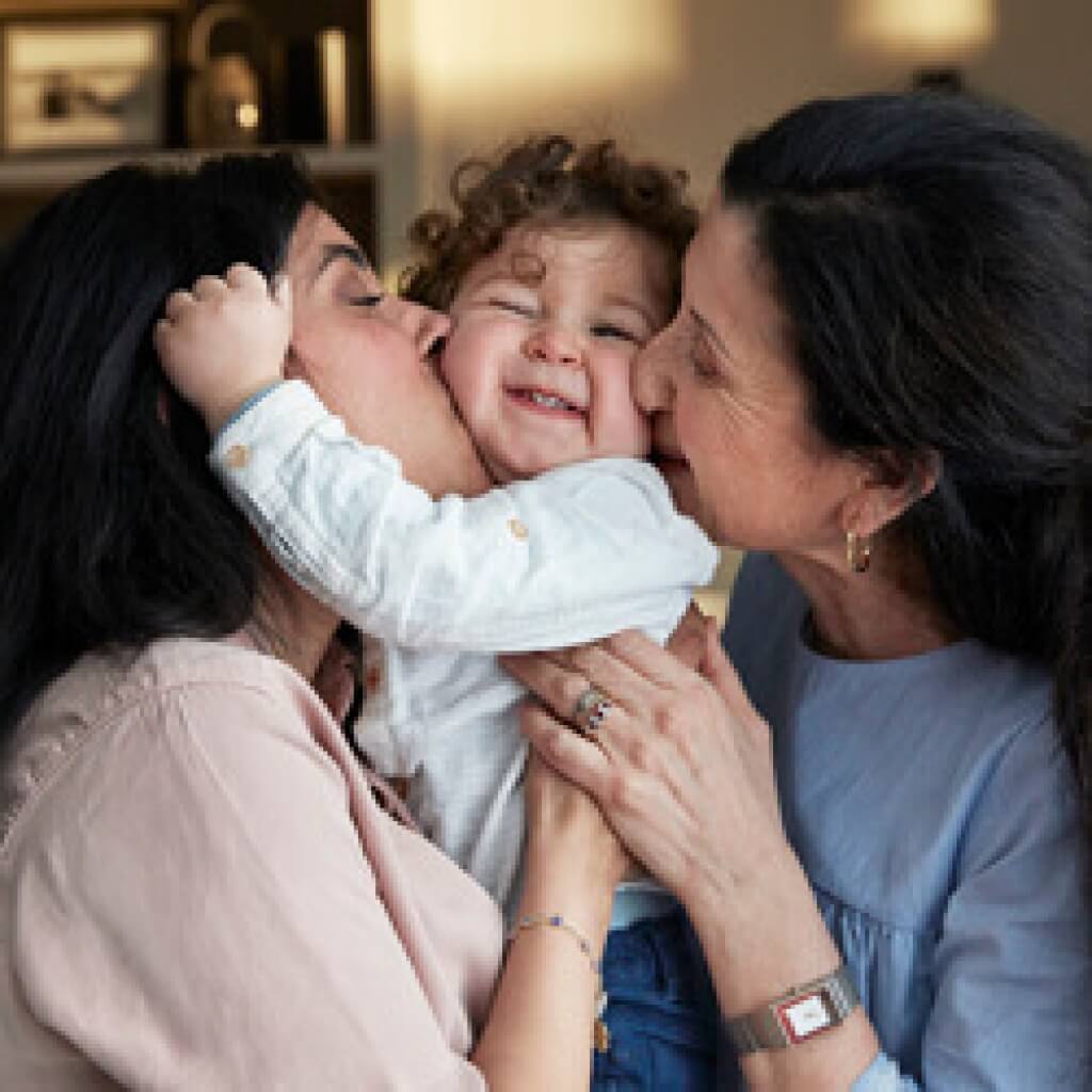 mom and grandma kissing child