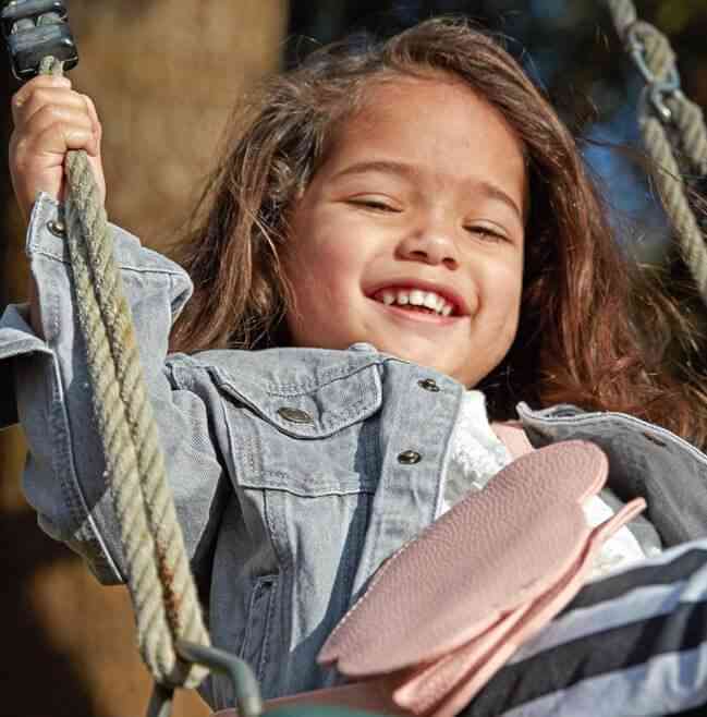 Toddler laughing while on a swing