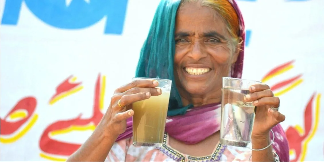 Woman holding two glasses of water: one not purified and one clear and purified