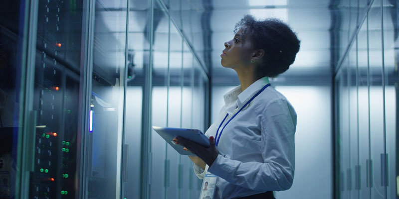 female network engineer working in data center servers rack
