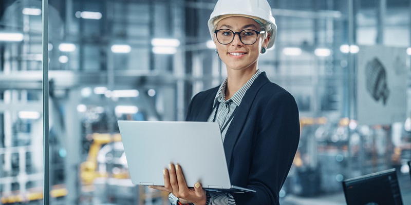 Woman holding a laptop wearing a workhat