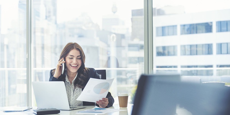 Happy business woman talking on the phone and holding a report
