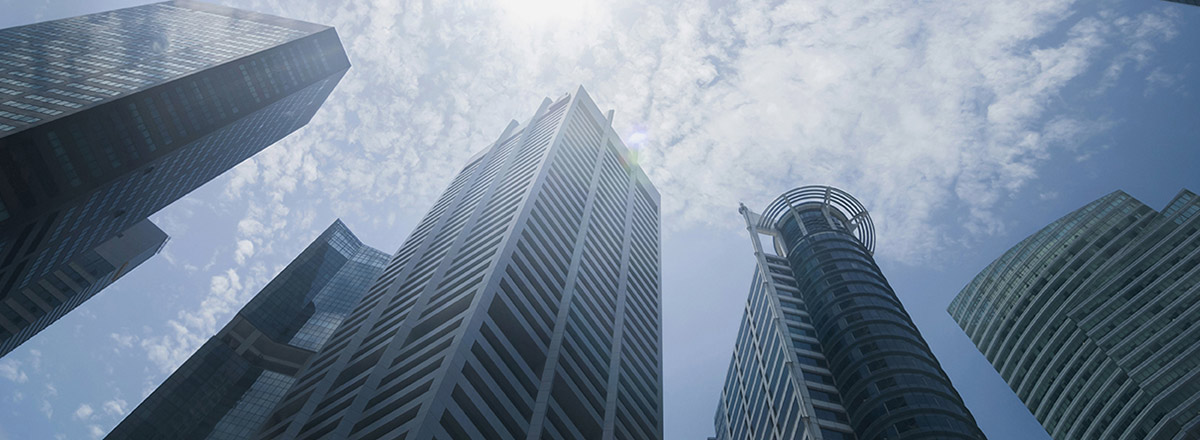 View from the ground to the top of several skyscrapers, with clouds above