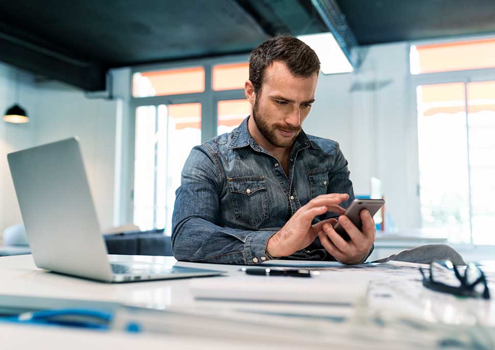 Man with laptop using smartphone