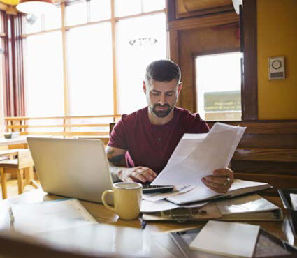 man working on laptop with papers