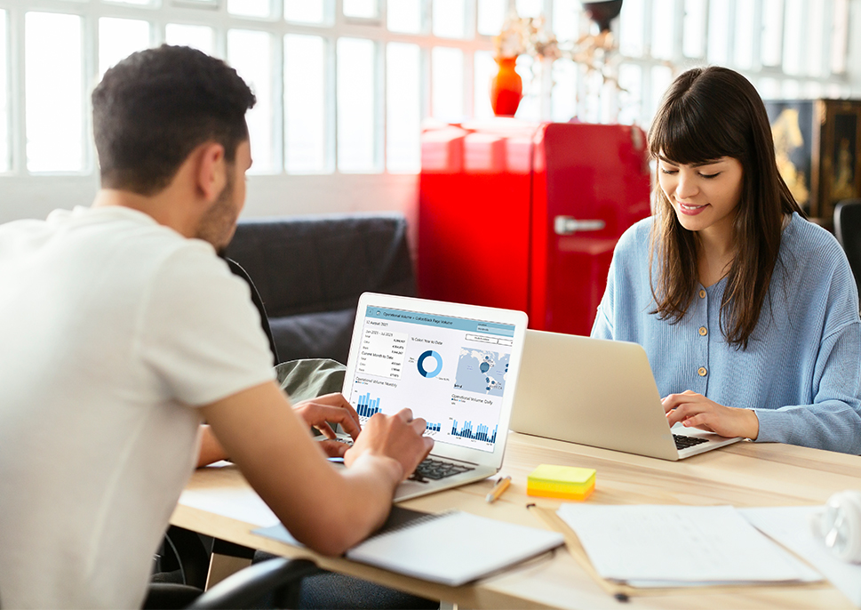 Man and woman sitting at desk with their laptops